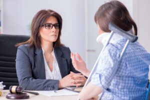 A personal injury lawyer in Palmdale meeting with an injured woman with a crutch and a neck brace.