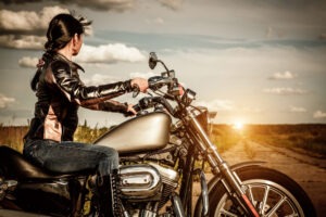 A woman, looking away from the camera, prepares to hit the road with her motorcycle.