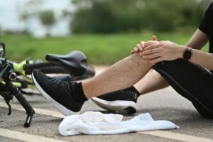 An injured cyclist holds his knee after an accident in Palmdale. A bicycle crash attorney can help riders collect financial compensation after a collision.